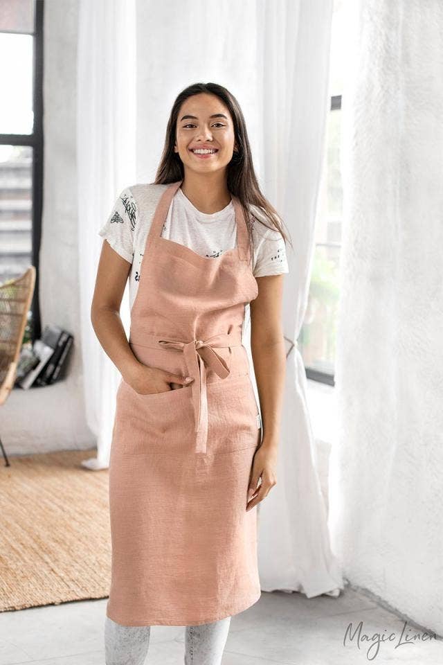 Woman in a charcoal grey linen bib apron with pockets, designed for cooking or gardening, exemplifying MagicLinen's stylish and functional unisex design.