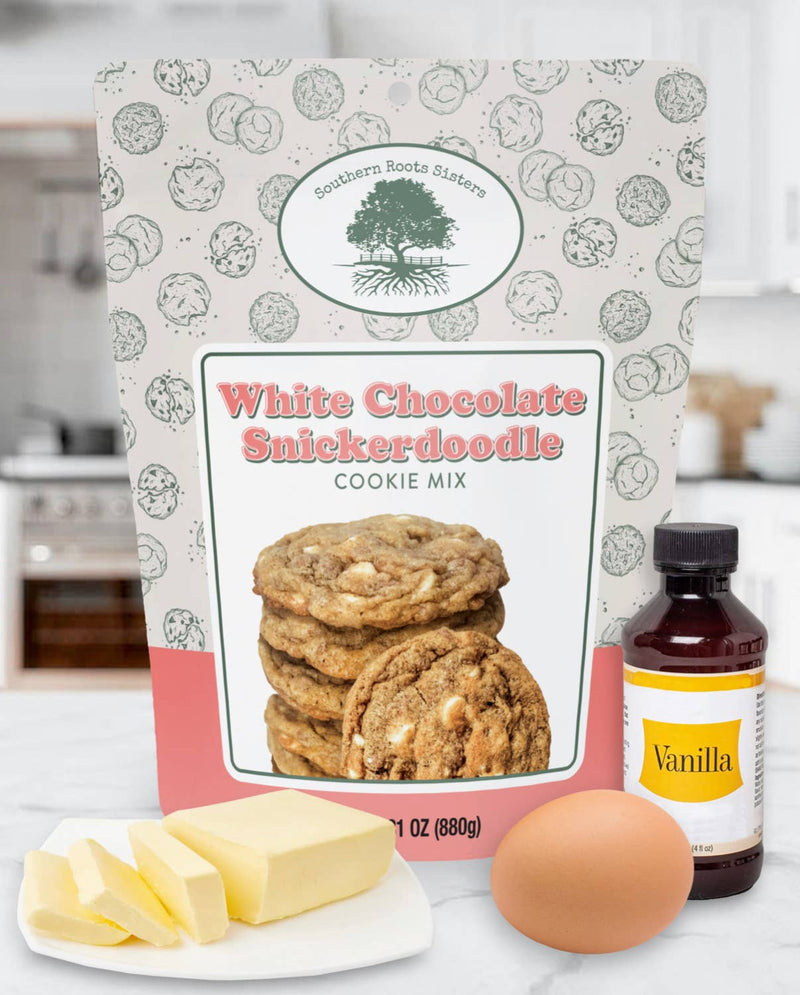 Southern Roots Sisters White Chocolate Snickerdoodle Cookie Mix with butter, egg, vanilla on marble countertop, ready for baking.