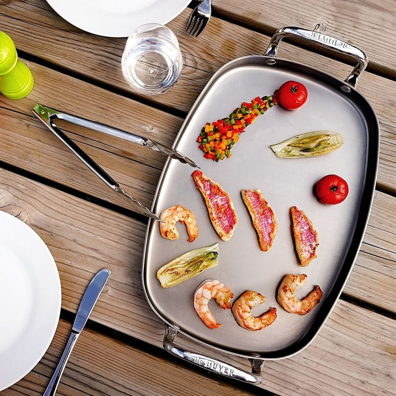De Buyer | Mineral B Element Rectangular Pan with two handles on a tray, showcasing its culinary use.