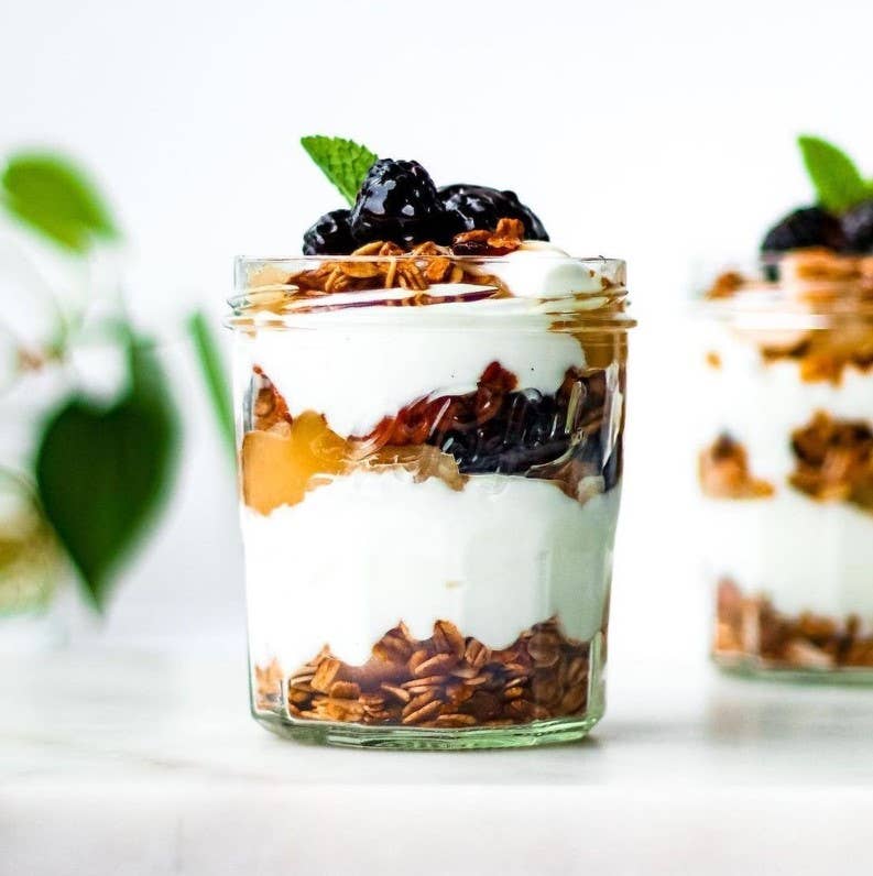 Le Parfait 324ml French Jam Jar filled with a yogurt parfait, showcasing layers of granola, yogurt, fruit compote, and berries, topped with mint.