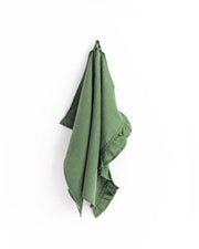 MagicLinen ruffle trim tea towel in moss yellow, hanging on a hook. Made from soft, durable linen with ruffle detailing, perfect for stylish kitchen use.