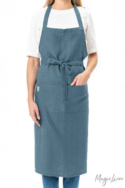 Person wearing MagicLinen - Charcoal Grey Linen Bib Apron with Pockets, ideal for cooking and gardening, showcasing its stylish and functional design.