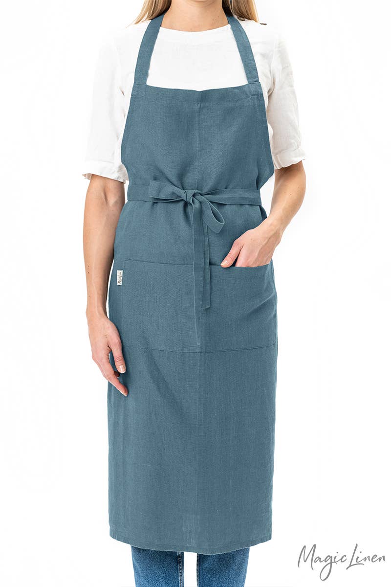 Person wearing MagicLinen - Charcoal Grey Linen Bib Apron with Pockets, ideal for cooking and gardening, showcasing its stylish and functional design.