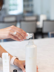 Person pouring L'AVANT Collective - Fresh Linen Multipurpose Cleaner Refill into a bottle, showcasing eco-luxe packaging and easy refill process for sustainable cleaning.