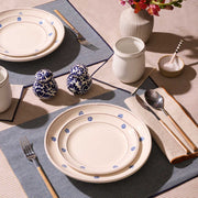 ATELIER SAUCIER - Dune Napkins in a folded display with wooden-handle cutlery, enhancing a chic, natural table setting with blue floral-edged ceramic plates and a floral vase.