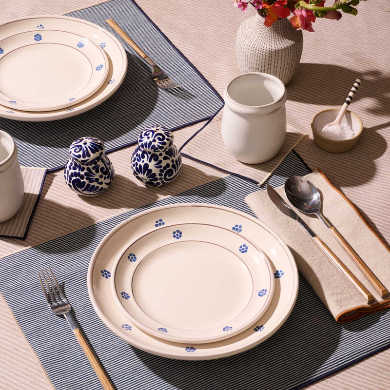 ATELIER SAUCIER - Dune Napkins in a folded display with wooden-handle cutlery, enhancing a chic, natural table setting with blue floral-edged ceramic plates and a floral vase.