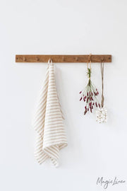 Linen tea towel on a hook, highlighting its texture and loop for hanging, perfect for kitchen use.