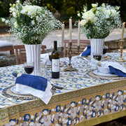 Couleur Nature - Forest Harvest Mustard & Blue tablecloth elegantly sets an outdoor dining table, featuring Provençal-inspired patterns amidst a sophisticated garden gathering.