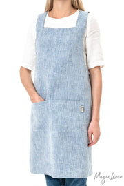 Woman wearing MagicLinen's pinafore cross-back linen apron, featuring a twin-sectioned front pocket, ideal for cooking or gardening, offered by Athens Cooks kitchen store.
