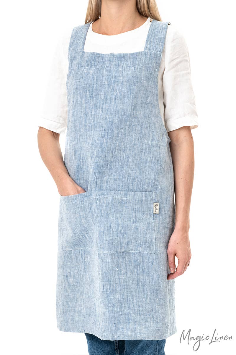 Woman wearing MagicLinen's pinafore cross-back linen apron, featuring a twin-sectioned front pocket, ideal for cooking or gardening, offered by Athens Cooks kitchen store.