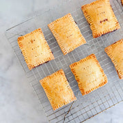 FarmSteady - Pastry Tart Making Kit: Six golden-brown, homemade-style hand pies cooling on a wire rack, showcasing crimped edges and vent holes.