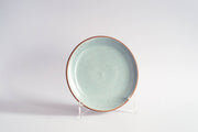 RachaelPots - Salad Plate: Yellow, featuring a pale-blue speckled glaze and natural brown rim, displayed upright, highlighting its handcrafted, unique design. Perfect for enhancing your table setting.