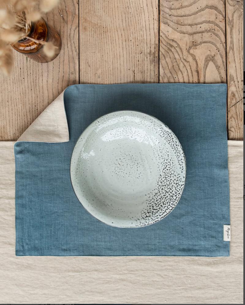 Double layer linen placemat set of two, displayed under a ceramic plate on a wooden surface, highlighting its elegant texture and craftsmanship.