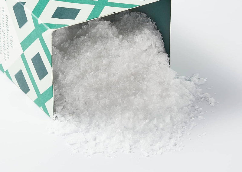 Wholesome Good - Maldon Sea Salt 8.5oz carton tipped over, spilling flaky sea salt crystals, showcasing premium cooking essentials from Athens Cooks, a curated kitchen store.
