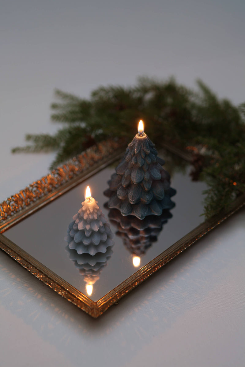 Mo&Co Home Exclusive: Sculpted Beeswax Trees—two carved candles on an ornate mirror reflecting their flames, showcasing artistry and elegance in two sizes for holiday ambiance.