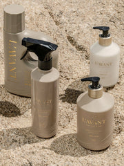 L'AVANT Collective - Hand Soap Ambre Santal, part of a neutral-toned set, showcased on a sandy surface, highlighting its eco-luxe, plant-based, and reusable glass bottle design.
