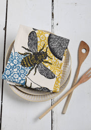 Hearth and Harrow - Honeybee Tea Towel on ceramic plates, showcases organic cotton with a vintage bee print, ideal for kitchen decor.