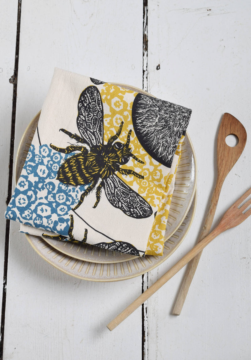 Hearth and Harrow - Honeybee Tea Towel on ceramic plates, showcases organic cotton with a vintage bee print, ideal for kitchen decor.