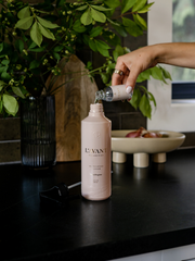 L'AVANT Collective Multipurpose Surface Cleaner in Blushed Bergamot scent, a hand pouring liquid into a luxury refillable bottle for versatile cleaning use.