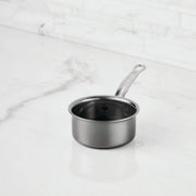 Hestan | Cookware, .75qt Butter Warmer Pan, a stainless-steel saucepan with a long handle, on a marble countertop, ideal for precise melting and cooking.