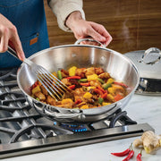 Hestan Provisions 14 Stainless Steel Dome Lid in use, covering a stir-fry in a stainless-steel sauté pan, showcasing its secure fit and cooking performance.