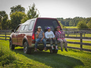 Beth's Farm Kitchen - Farm Ketchup - Low Sugar, showcased with a red pickup and relaxed group, embodies local, vegan, gluten-free ingredients perfect for diverse food pairings.