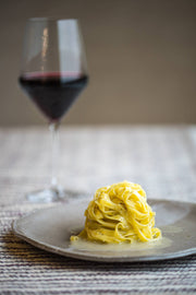 TartufLanghe - Tartufissima® N°19 Truffle Pasta elegantly served with red wine, showcasing its gourmet, truffle-rich flavor on a refined stoneware dish.