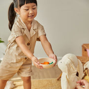 Girl holding a bowl from the PlanToys Kids Pretend Playtime Tableware Toy Set, ideal for imaginative play and enhancing dining experiences for toddlers.