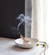 Gravesco Pottery - Palo Santo Burning Ritual Dish: Black, showcasing a partially burned smudge stick, delicate buds beside, on a wooden surface, embodying mindful, handcrafted elegance.
