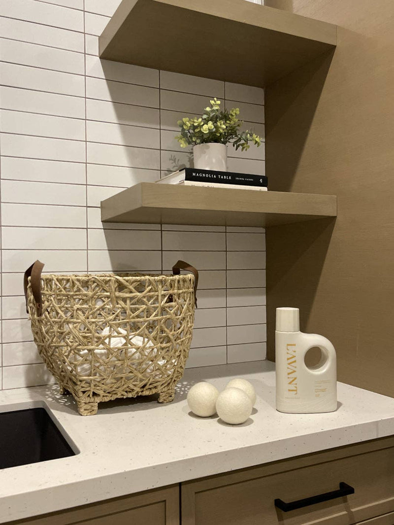 L'AVANT Collective - Laundry Detergent Fresh Linen on counter with dryer balls, wicker basket, and plant, embodying eco-friendly, gentle fabric care in a chic, minimalist setup.