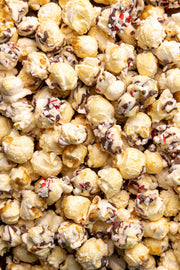 Poppy Hand-Crafted Popcorn - Peppermint Bark Popcorn, features popcorn coated in white chocolate, drizzled with dark chocolate, and topped with crushed peppermint candies, perfect for holiday indulgence.