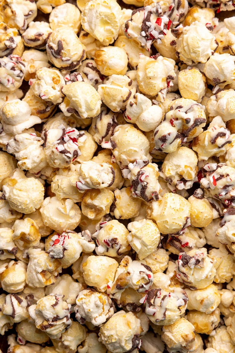 Poppy Hand-Crafted Popcorn - Peppermint Bark Popcorn, features popcorn coated in white chocolate, drizzled with dark chocolate, and topped with crushed peppermint candies, perfect for holiday indulgence.