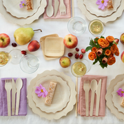 Overhead view of a styled table featuring bambu® Disposable Bamboo Knife, Fork, and Spoon Set on colored linen napkins, emphasizing eco-friendly, compostable dining options.