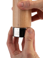 Peugeot | Isen Salt Mill, Natural, held in hands, showcases a wooden body with polished metal base featuring Peugeot lion logo and adjustable grind control ring.