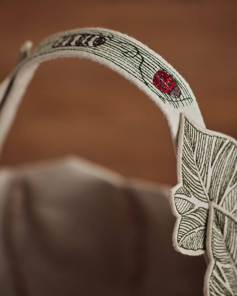 Coral & Tusk - Jack-o'-Lantern Basket handle close-up, showing felt appliqué with embroidered leaf veins and flower, reflecting a handcrafted Halloween design.