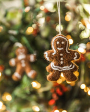 Farmhouse Pottery - Felted Gingerbread Ornament: Lady, handcrafted in Nepal, hangs on a Christmas tree, featuring intricate white icing details and a twine loop.