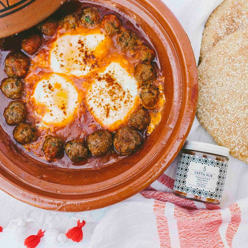 Villa Jerada - Kefta Rub - 50g jar beside a tagine of kefta meatballs with poached eggs, showcasing its use in Moroccan-style cooking.