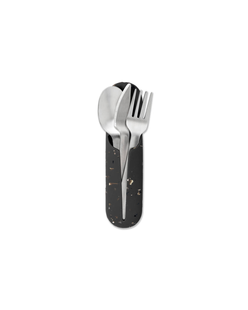 W&P - Stainless Steel Utensils Set in Silicone Carry Case: Terrazzo Charcoal, featuring a spoon, fork, and knife in a sleek black container for easy portability.