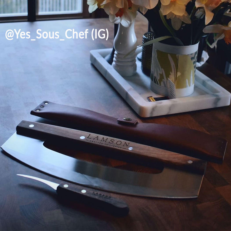 Lamson leather sheath for 14 pizza cutter/rocker displayed on a table, highlighting its purpose in storing and protecting kitchen tools.