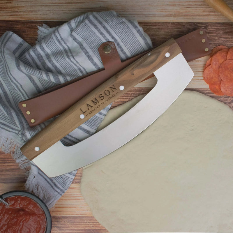 Lamson | 12 Pizza Rocker with Walnut Handles on pizza dough, highlighting its precise cutting capability for clean, intact slices.