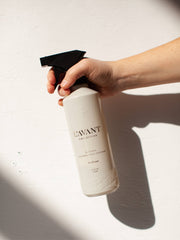 L'AVANT Collective - Fresh Linen Multipurpose Cleaner in a sleek, refillable spray bottle held by a hand, ideal for kitchen and bathroom cleaning.