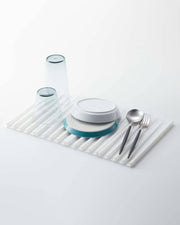 Yamazaki Home - Tower Folding Dish Drainer Mat in use, showcasing upside-down glasses, plates, and cutlery on a white silicone drying tray.