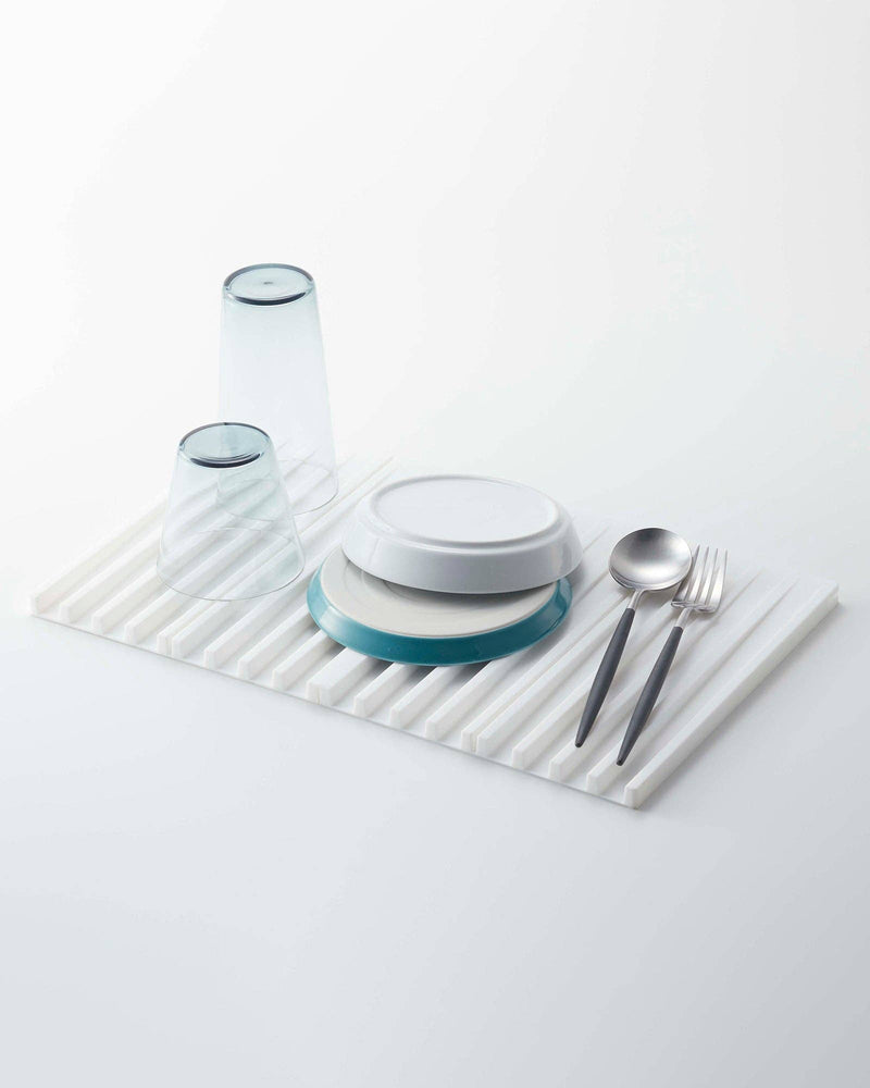 Yamazaki Home - Tower Folding Dish Drainer Mat in use, showcasing upside-down glasses, plates, and cutlery on a white silicone drying tray.