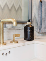 L'AVANT Collective - Fresh Linen Hand Soap in a sleek black glass bottle on a marble countertop, blending eco-luxe design with plant-based ingredients.