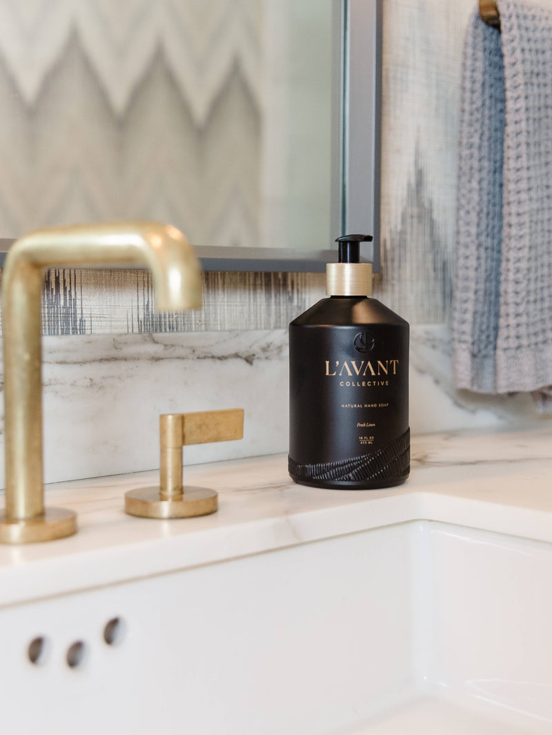 L'AVANT Collective - Fresh Linen Hand Soap in a sleek black glass bottle on a marble countertop, blending eco-luxe design with plant-based ingredients.