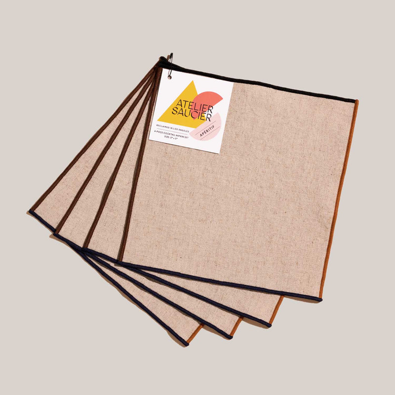 ATELIER SAUCIER - Dune Appetizer Napkins | Set of 4: Beige linen napkins with contrasting trims, clipped on a ring. Perfect for stylish gatherings.