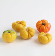 Artifaqt - Heirloom Tomato Beeswax Candle: Green / Small, displayed among yellow tomatoes, showcasing its natural beeswax craftsmanship and collaboration with Kneehigh Farm.