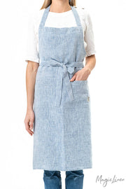 Woman wearing MagicLinen - Charcoal Grey Linen Bib Apron with Pockets, showcasing its unisex design, ideal for cooking or gardening.