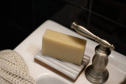 Gravesco Pottery - Soap Dish | White: Handmade ceramic dish on sink edge, holding soap, with a stainless-steel faucet nearby. Unique, Indianapolis-made, dishwasher safe.