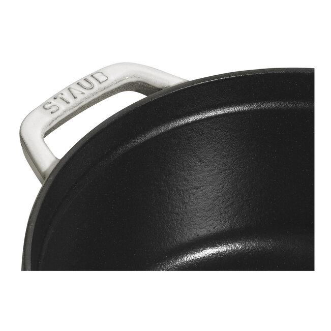 Staub | Round Cocottes - 5.5 qt White Truffle: Close-up of black enameled interior and white handle, branded STAUB, showcasing craftsmanship ideal for versatile cooking.